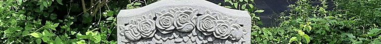 Nahaufnahme eines Rosen-Ornaments auf einem handwerklichen Grabmal aus belgischem Blaustein